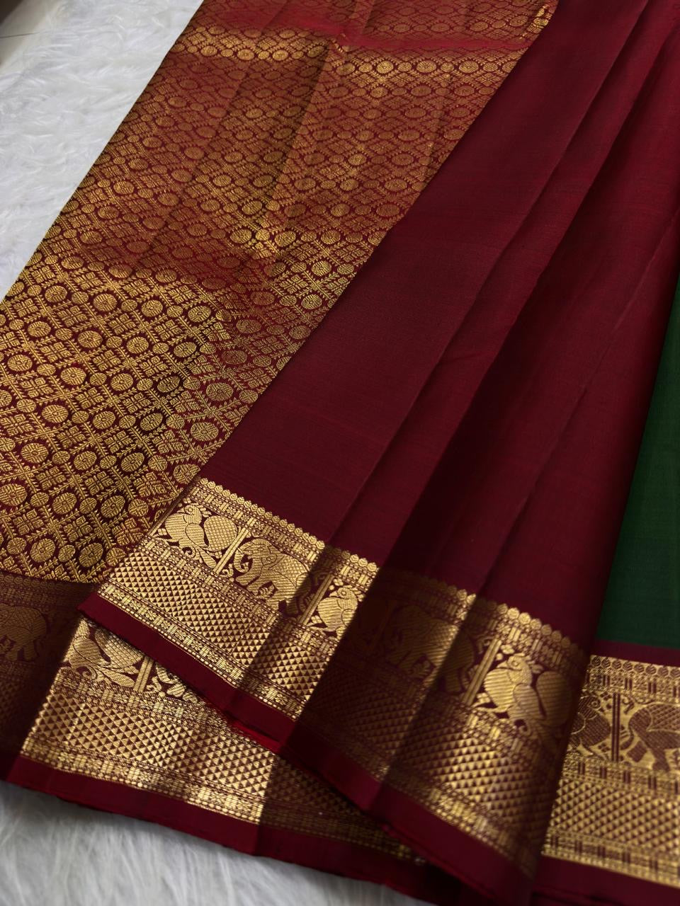 Full drape view highlighting the green body, contrast border and traditional zari workmanship.