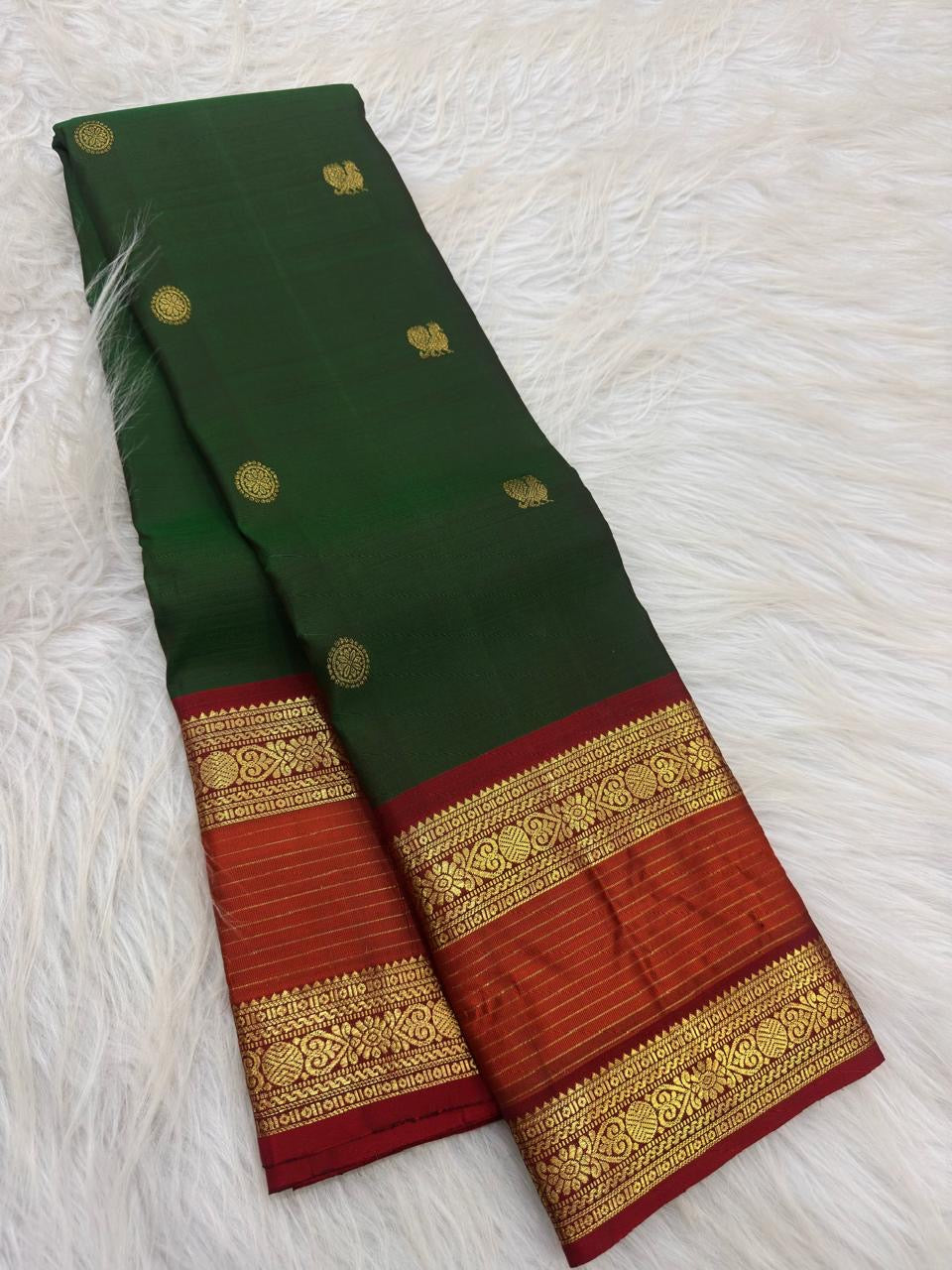 Detail of the saree border: A prominent Rettapet twin-register border in red, orange-red and gold, with Pavun motifs and stylised floral foliage arranged through the ornamental bands.
