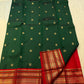 Folded deep green Kanchipuram silk saree showing rich silk body with gold zari buttas and red border — Idam Living