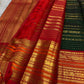 Detail of the saree border: A broad red to orange-red Varisaipet border built in repeated zari bands, with dense traditional geometric and figurative ornament arranged in architectural layers.