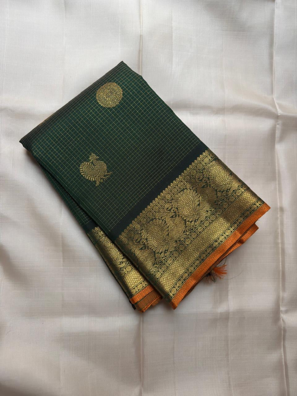 Round ornamental gold zari medallions alternating with bird-inspired buttas across the dark green body.