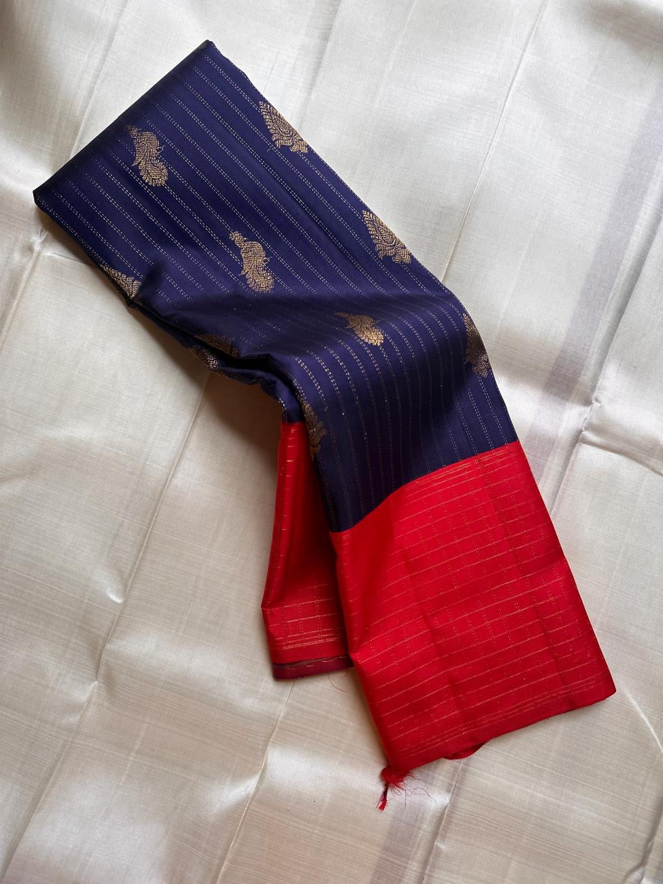 Deep indigo handwoven Pure Silk Kanchipuram korvai saree folded to show the vermilion shot border