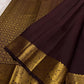 Dark brown Kanchipuram silk saree with small gold zari buttas and intricate Mayil border