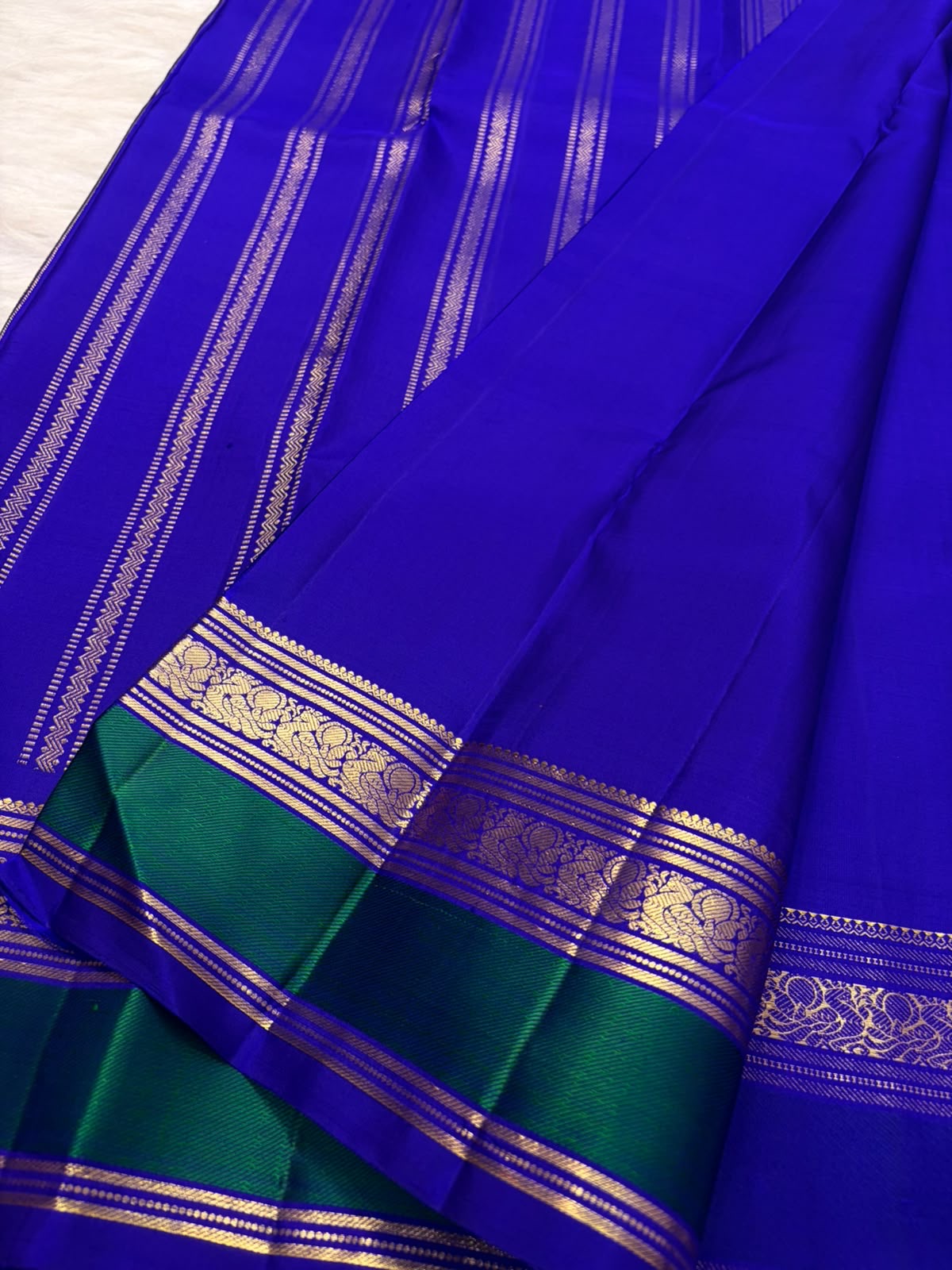 Vivid Neelam Blue and Emerald Green pure silk Kanchipuram Varisaipet saree, close-up of gold-toned woven ornament.