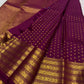 Close view of small circular gold zari buttas arranged across a deep cherry red-purple Kanchipuram silk body.