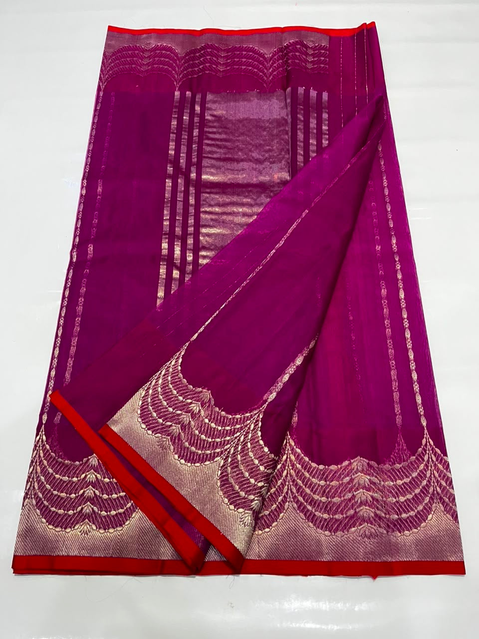 Scalloped feather-and-wave border detail with red trim on deep magenta Katan Silk Chanderi saree