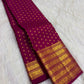 Folded deep cherry red Kanjivaram silk saree with evenly spaced circular gold zari buttas and an ornate border.
