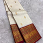 Warm ivory Kanchipuram silk body with individually spaced classic-gold zari buttas across an open field.