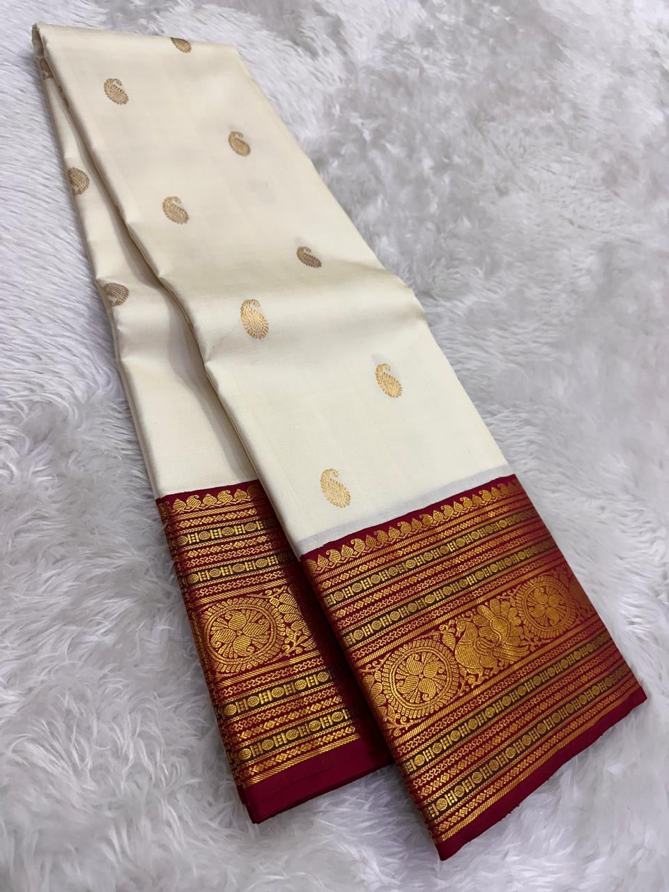 Warm ivory Kanchipuram silk body with individually spaced classic-gold zari buttas across an open field.