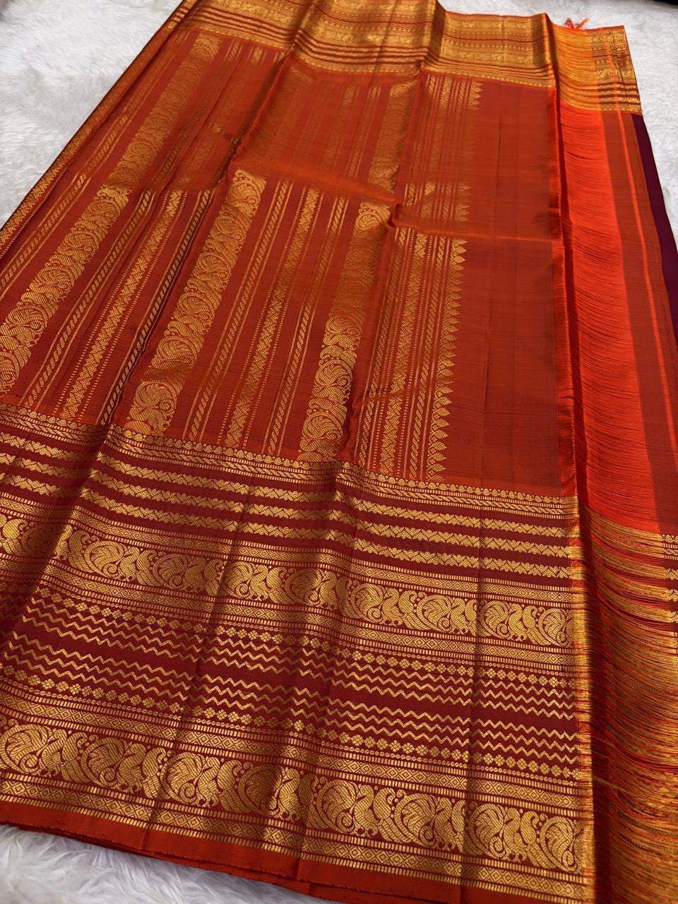 Rust orange Varisaipet border with red silk thread woven motifs on deep maroon Kanchipuram saree