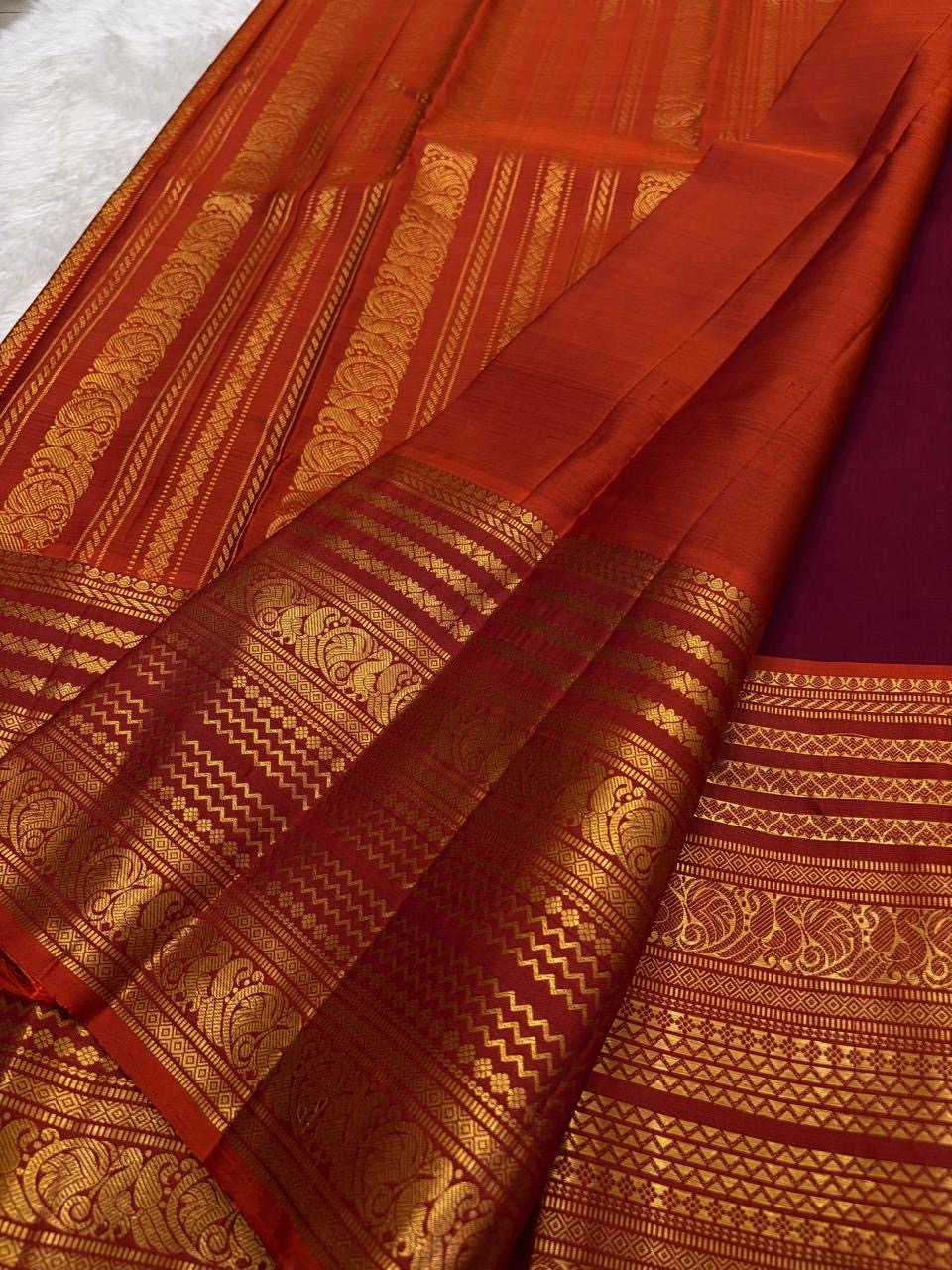 Rust orange pallu with red silk thread motifs on deep maroon Varisaipet Kanchipuram saree