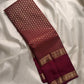 Dense antique-gold Kanchipuram pallu showing a fine geometric zari field against deep garnet silk.