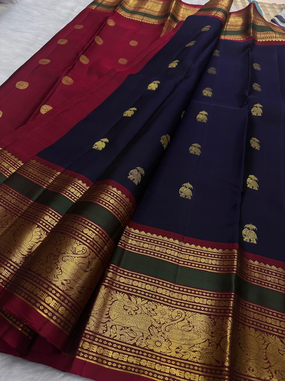 Deep navy Kanchi Pattu saree showing the contrast maroon-olive zari border.