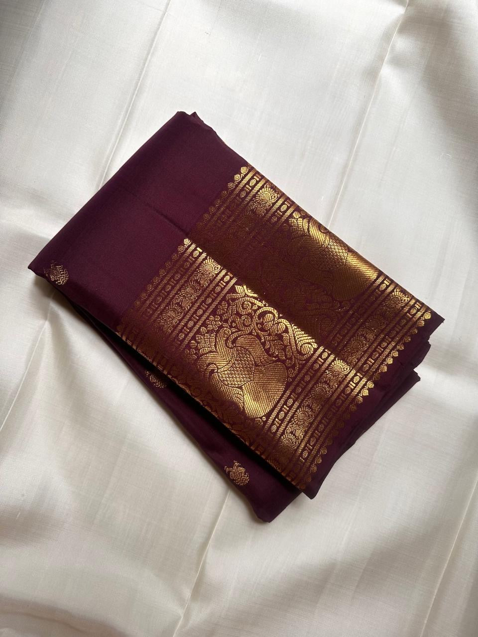 Broad Mayil-inspired classic-gold zari border against dark Paaku Kanchipuram silk.