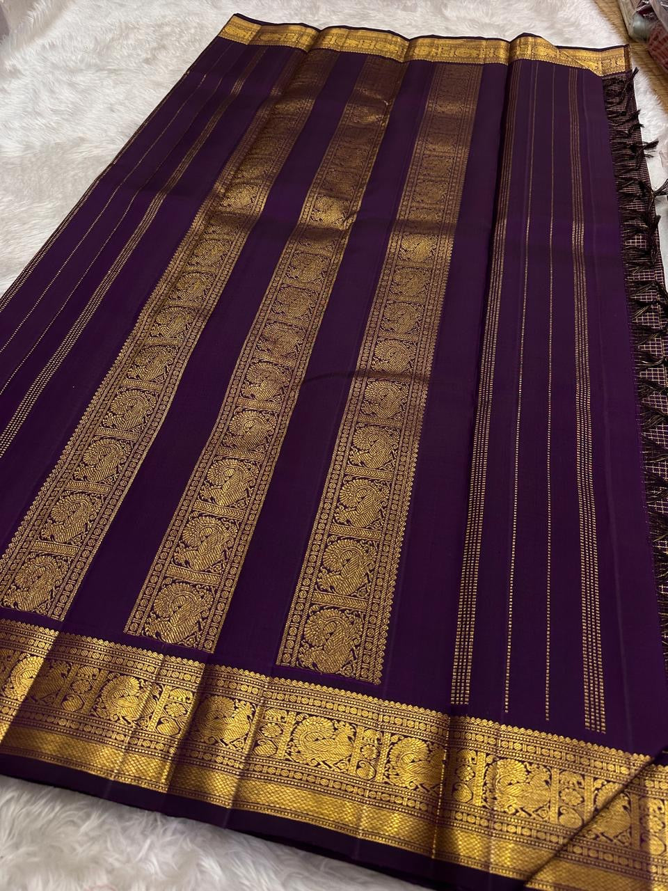 Deep purple Kanjipuram Zari Kattam saree folded flat showing luminous gold check weave and grand border — Idam Living