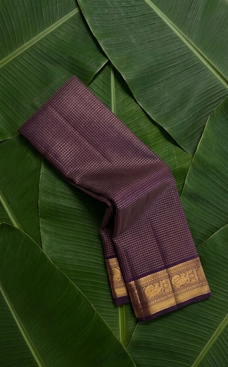 Deep purple Zari Kattam Kanchipuram silk saree rolled showing all-over gold zari check body and Maanga Mayil border — Idam Living