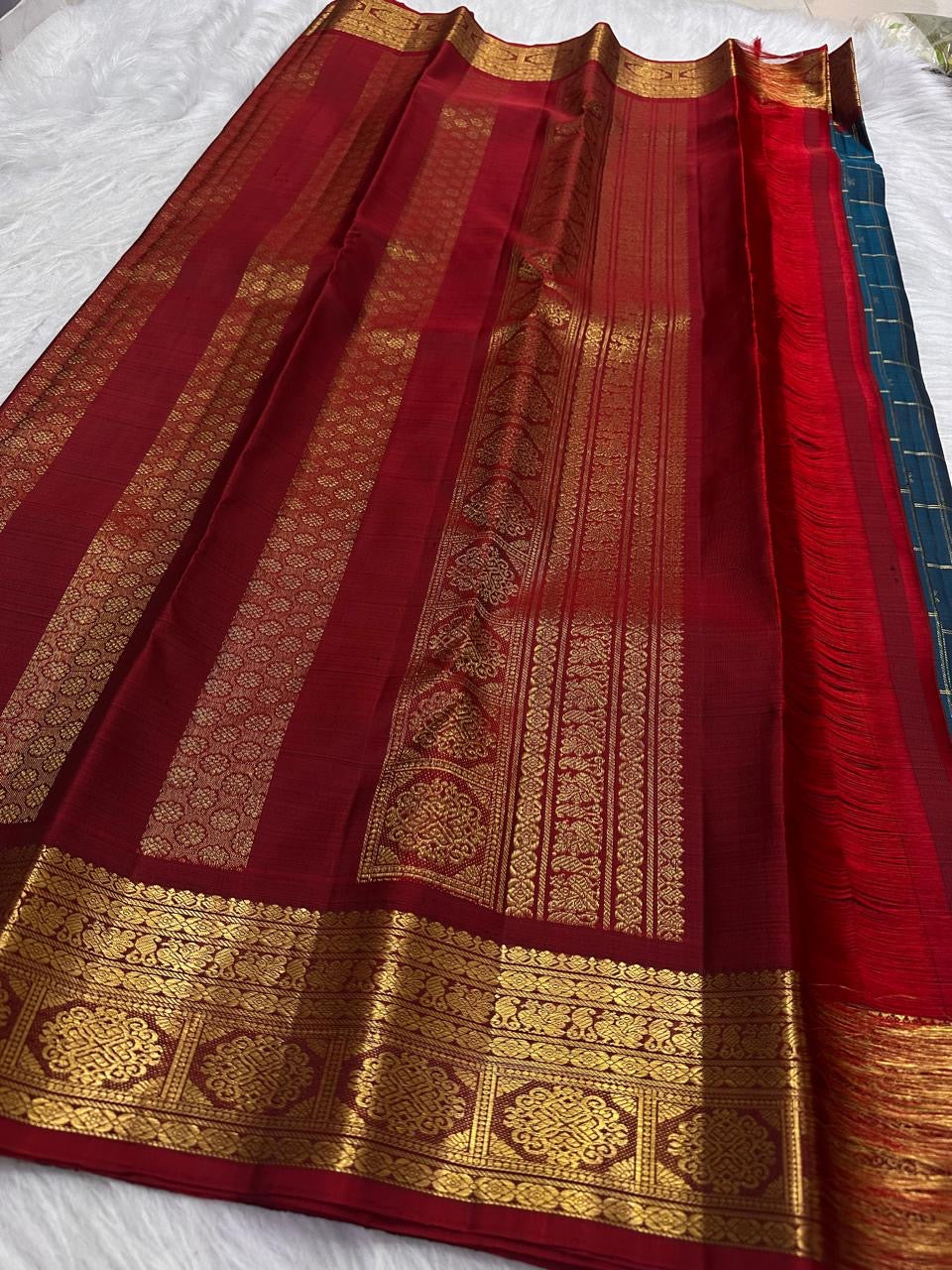 Subtle Deep Red accent edging the gold zari border of the Peacock Teal Kancheepuram saree.
