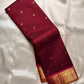 Deep red silk saree draped lengthwise showing scattered gold buttas and broad zari woven border.