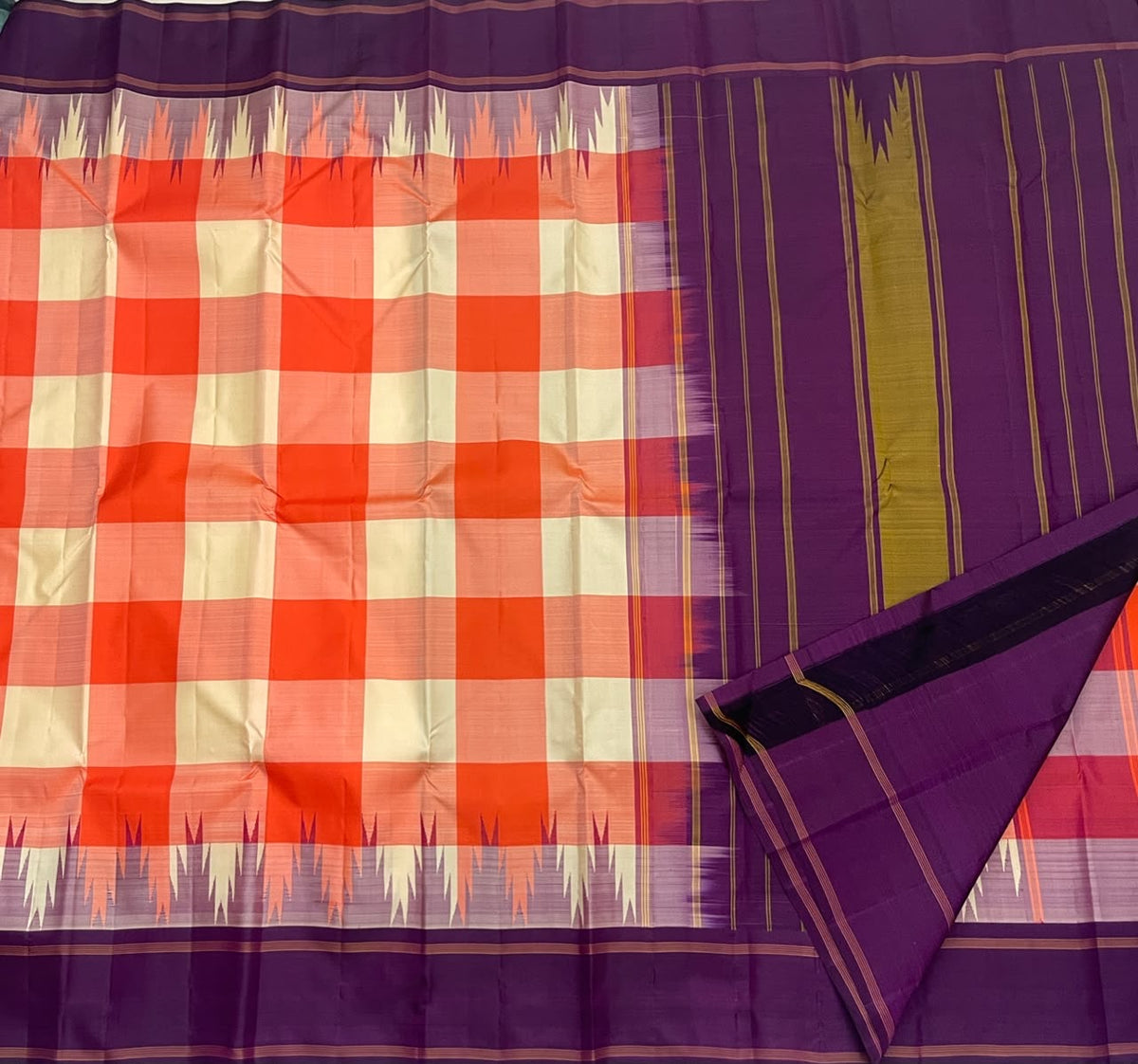 Deep violet pallu of the coral orange Kanchi Kattam silk saree
