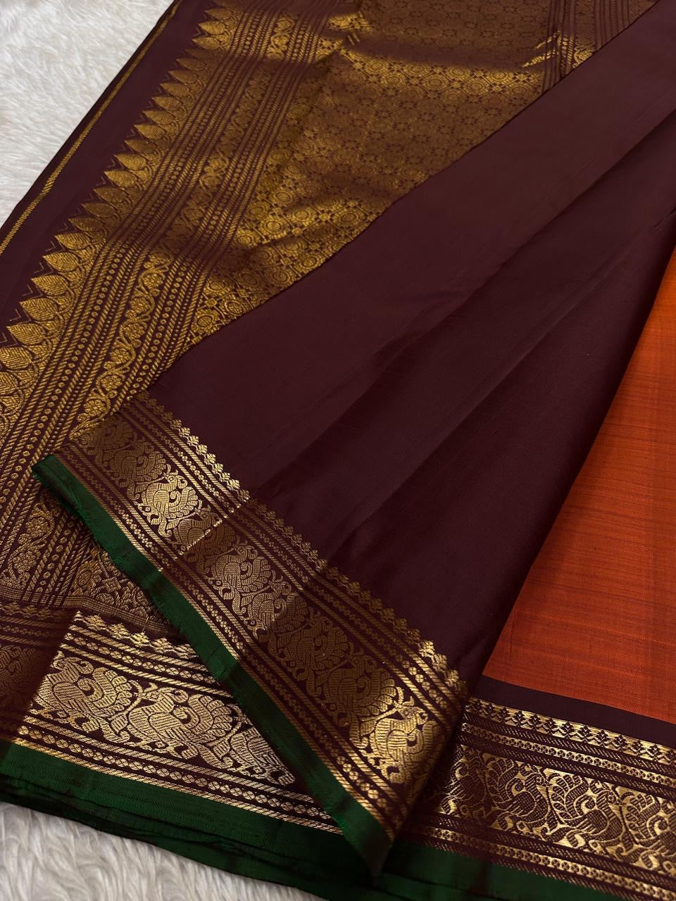Close view of deep maroon pallu with intricate zari woven design and a wide zari woven border panel with green edge finish.