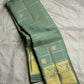 Gold Zari Kattam checks on the dewdrop sage green Kanjeevaram silk saree.