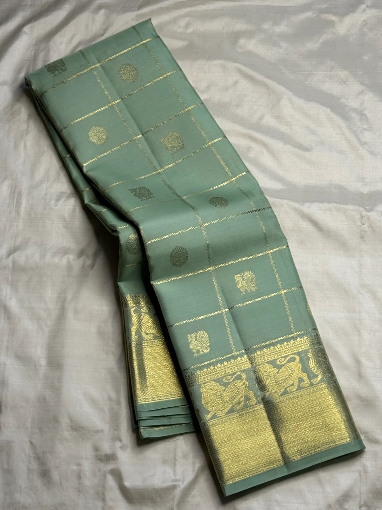 Gold Zari Kattam checks on the dewdrop sage green Kanjeevaram silk saree.