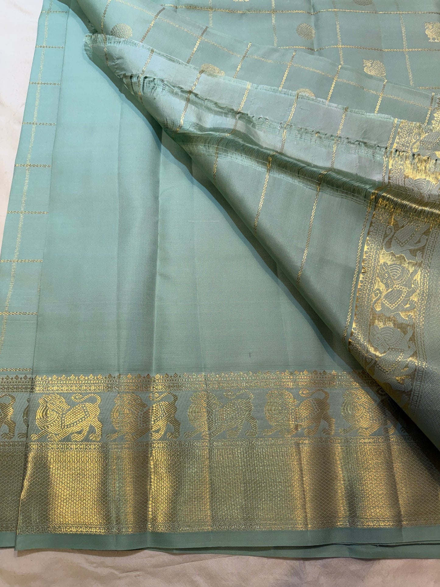 Dewdrop sage green Kanjeevaram saree showing Mayil and Kamalam zari buttas throughout.