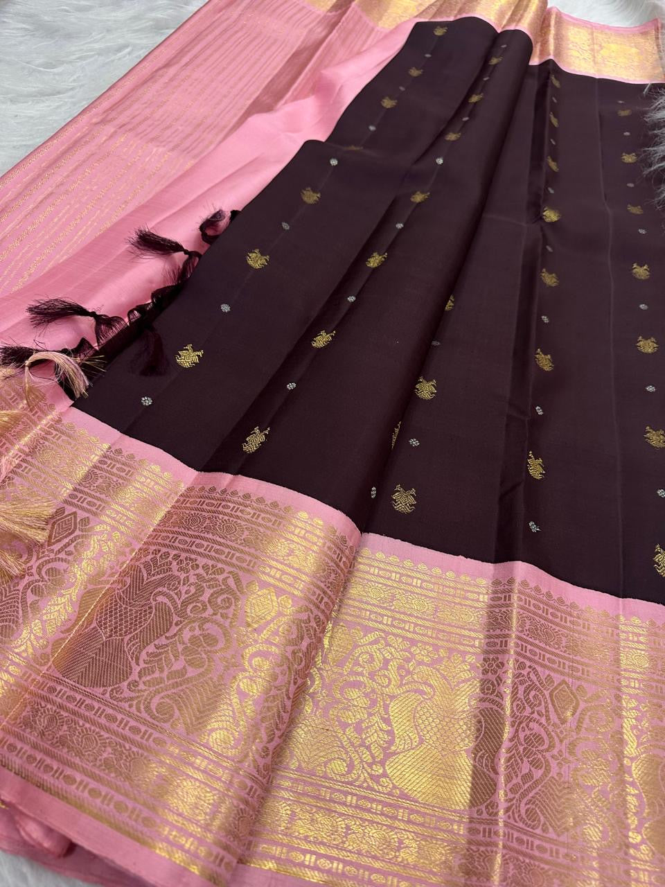 Close view of gold zari peacock motifs woven across a Dusty Rose Pink Kanchipuram Korvai border.