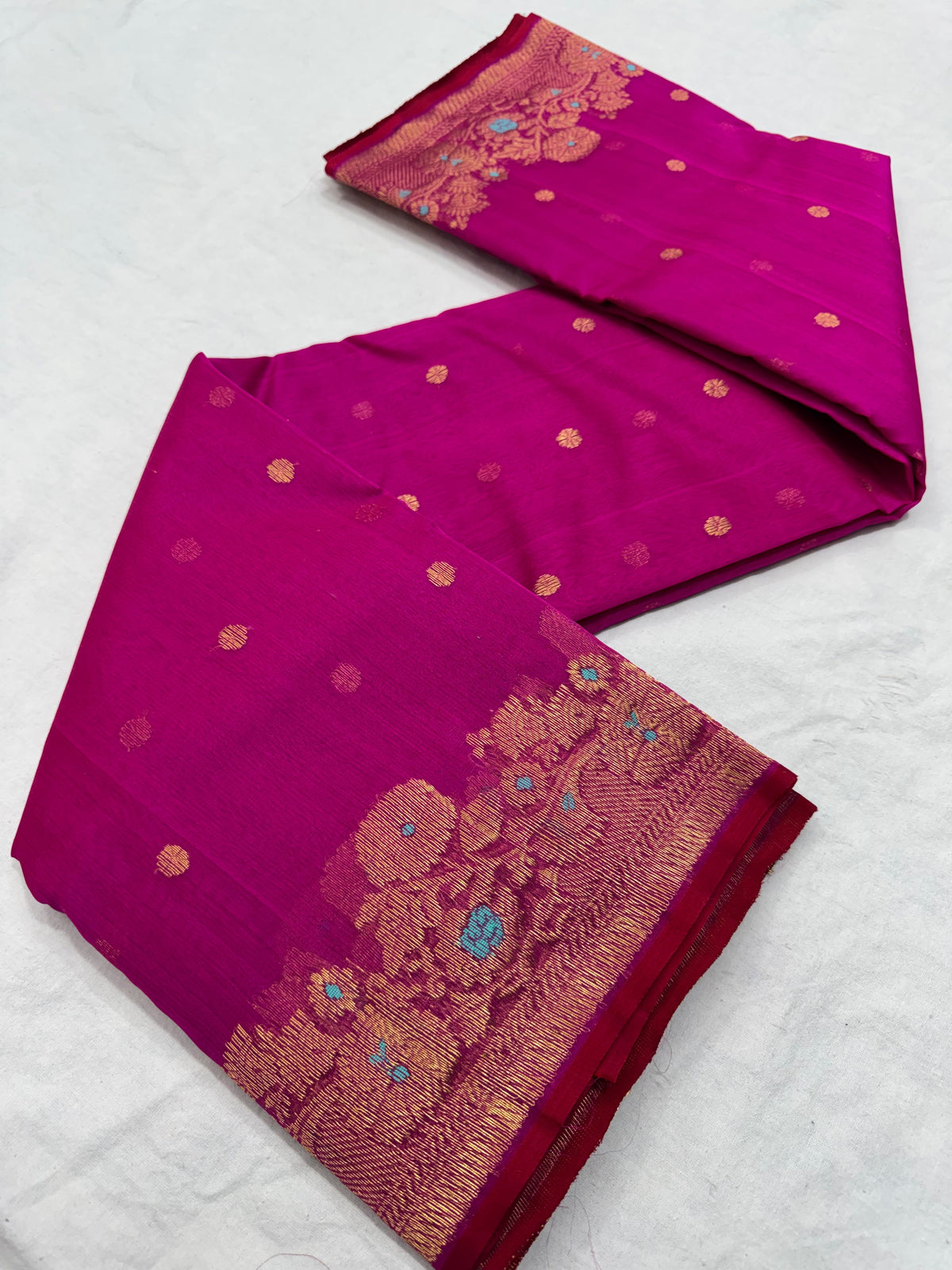 Folded purplish pink Katan silk Chanderi saree showing the gold-toned buttas and ornate floral border