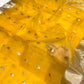 Close view of the turmeric yellow Chanderi body with pale buttas and green accents near the silver-toned border