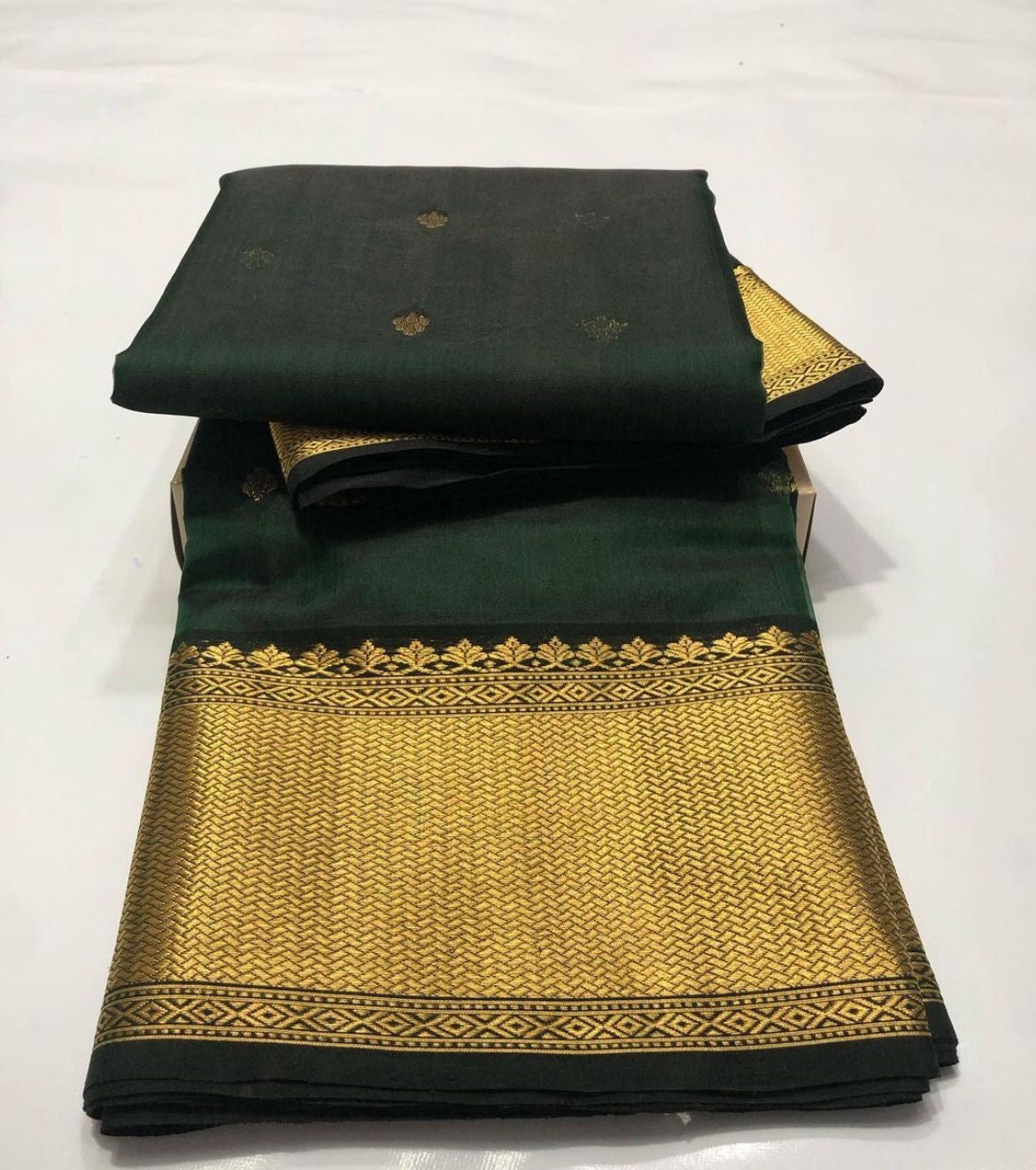 Draped Emerald Green handloom Chanderi saree showing petite gold buttas and expansive antique-gold woven pallu.