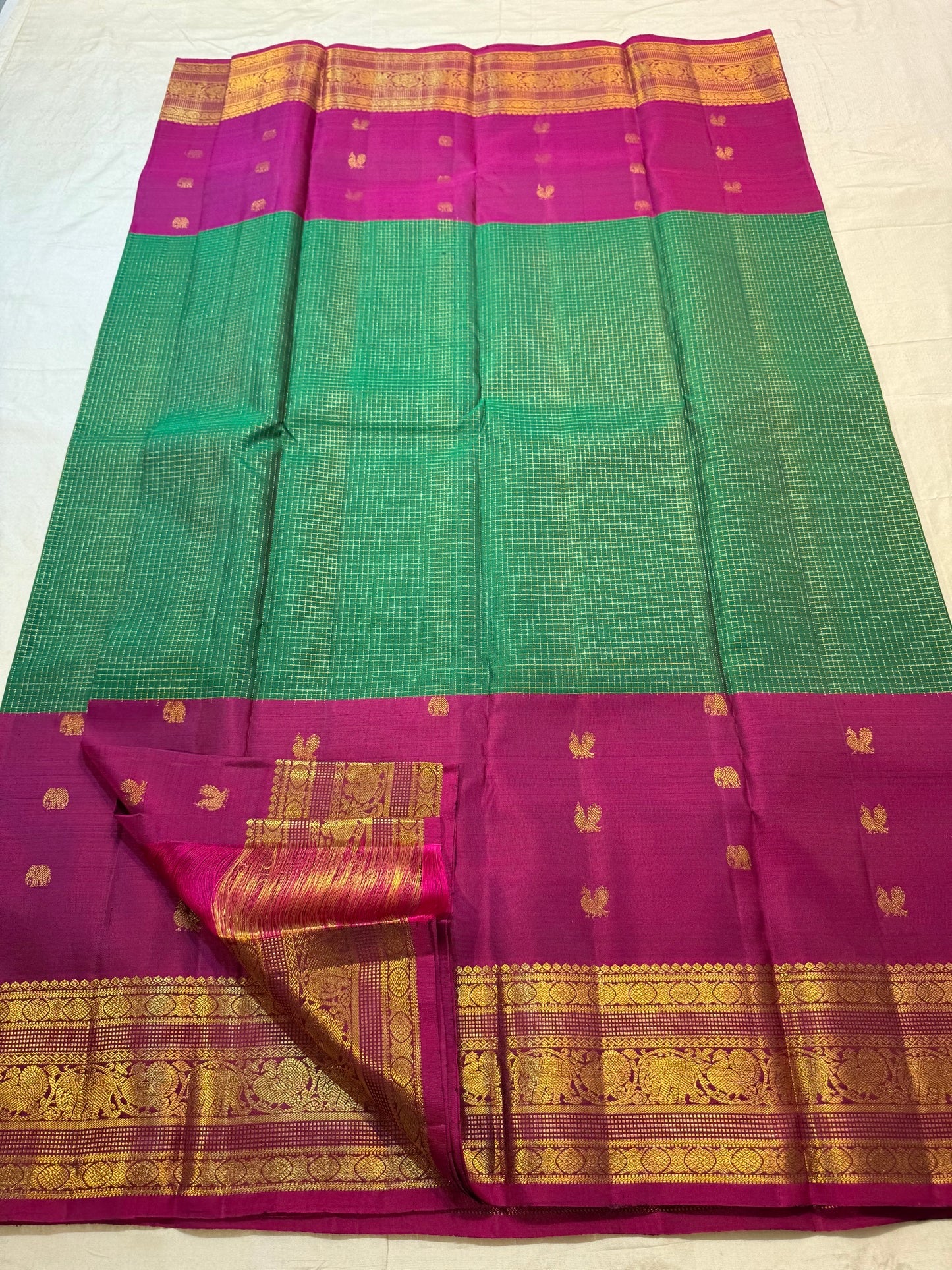 Close view of elephant and circular Chakram zari buttas across Emerald Pachai Green silk.