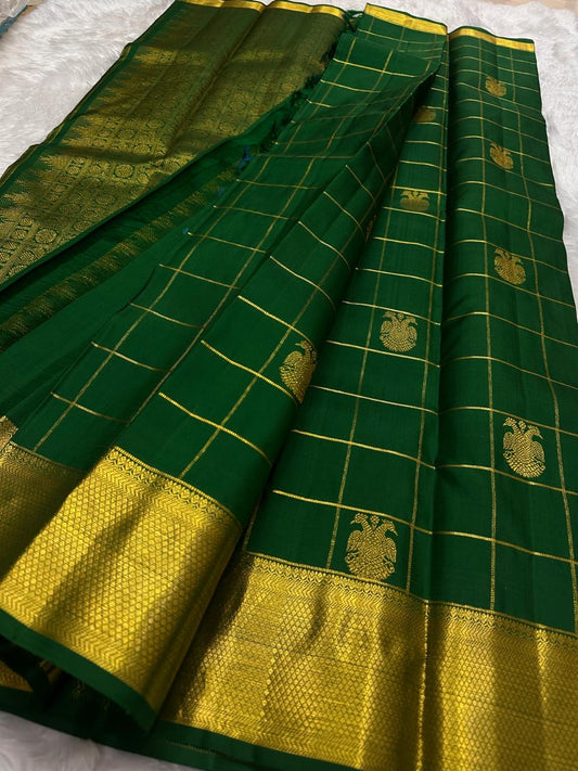 Deep emerald green pure silk Kanchipuram saree with gold Zari Kattam checks, handwoven Gandaberunda motifs and broad antique gold zari border.