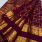 Pure Silk Kanchipuram in burnished lac-maroon with a subtle plum cast and structured traditional gold checks.