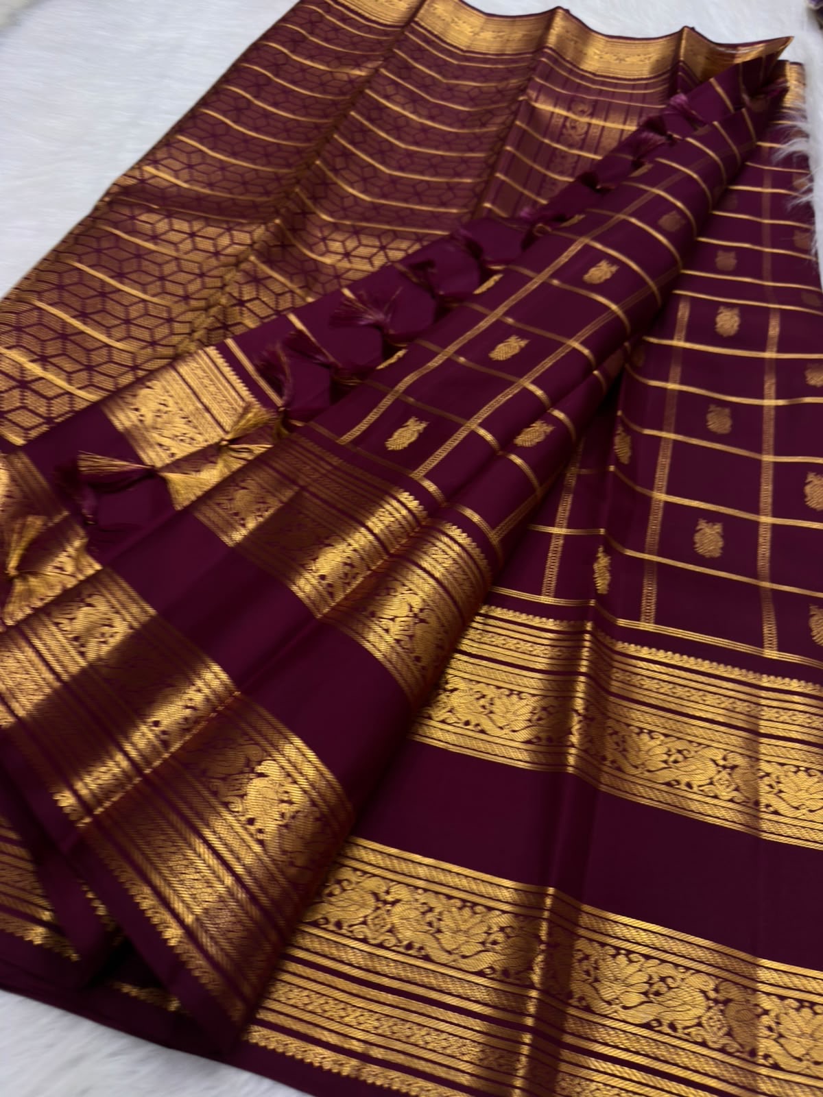 Pure Silk Kanchipuram in burnished lac-maroon with a subtle plum cast and structured traditional gold checks.