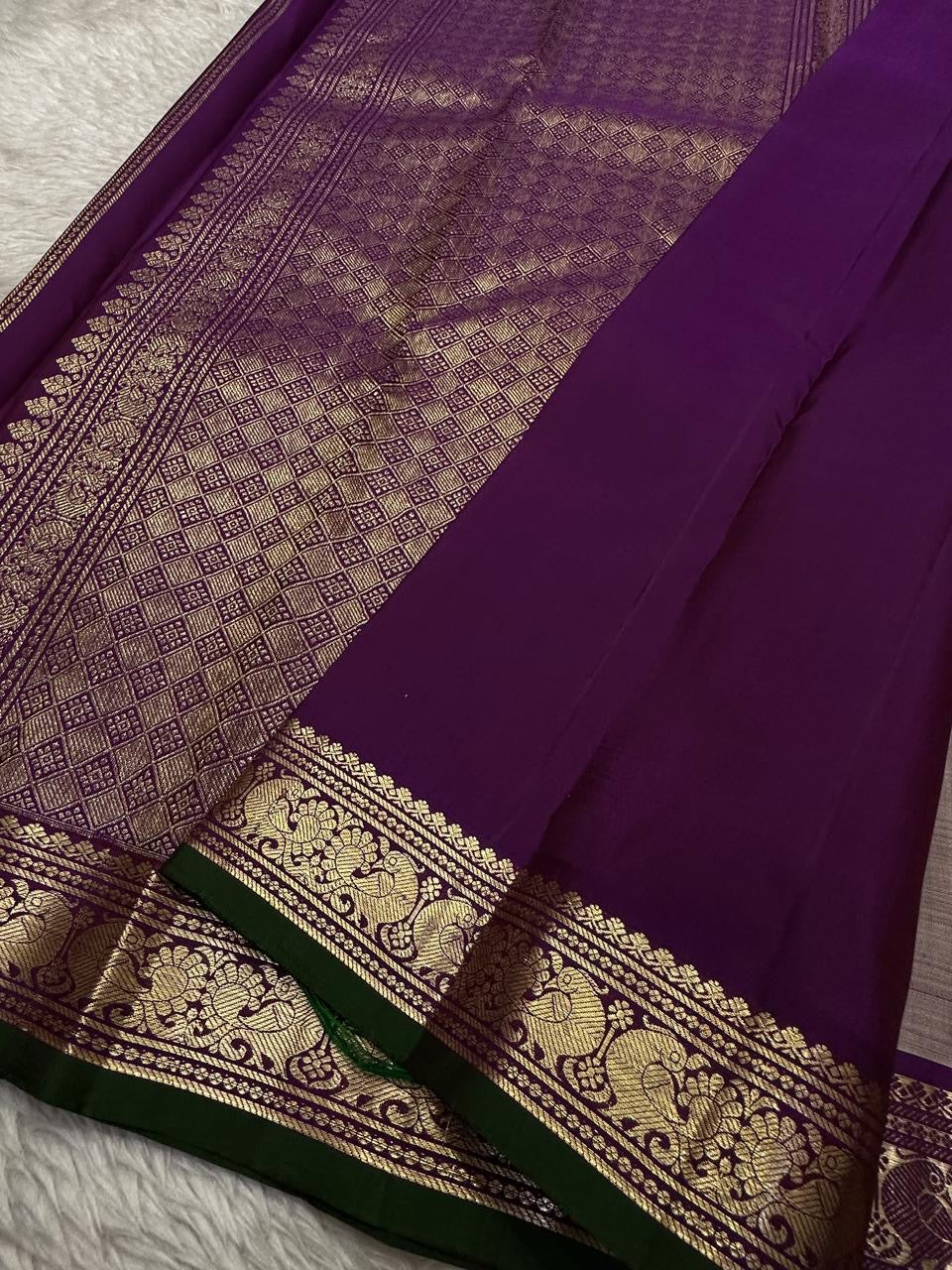 Close view of purple pallu with dense gold zari woven geometric grid and ornate border detailing.