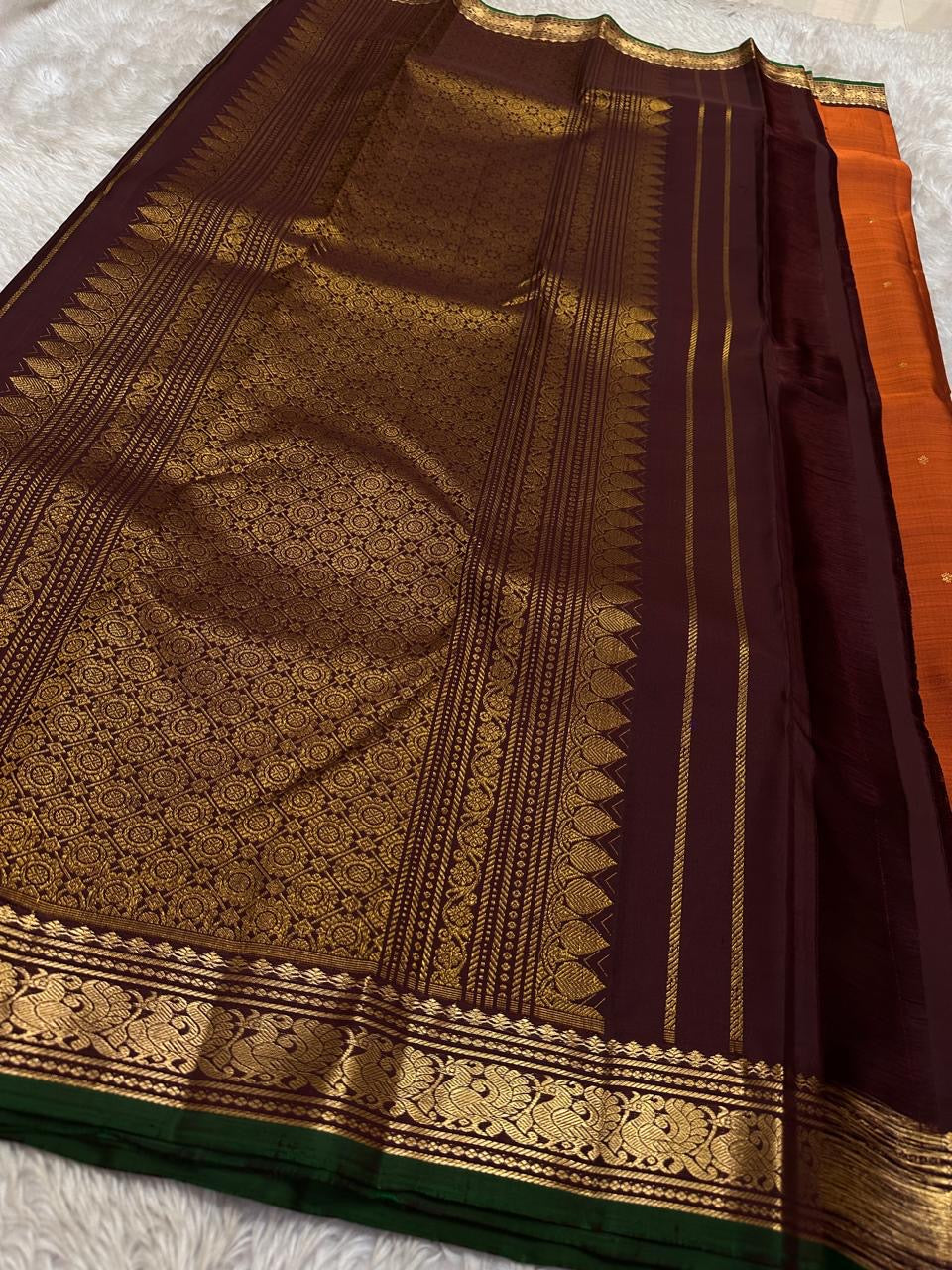 Close view of deep maroon pallu with intricate zari woven design and a wide zari woven border panel with green edge finish.