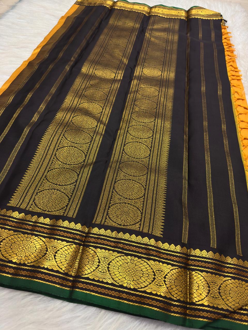 Turmeric yellow Kanchi Pattu saree folded with black and gold Kai Korvai border, lotus zari pallu and turmeric tassels.