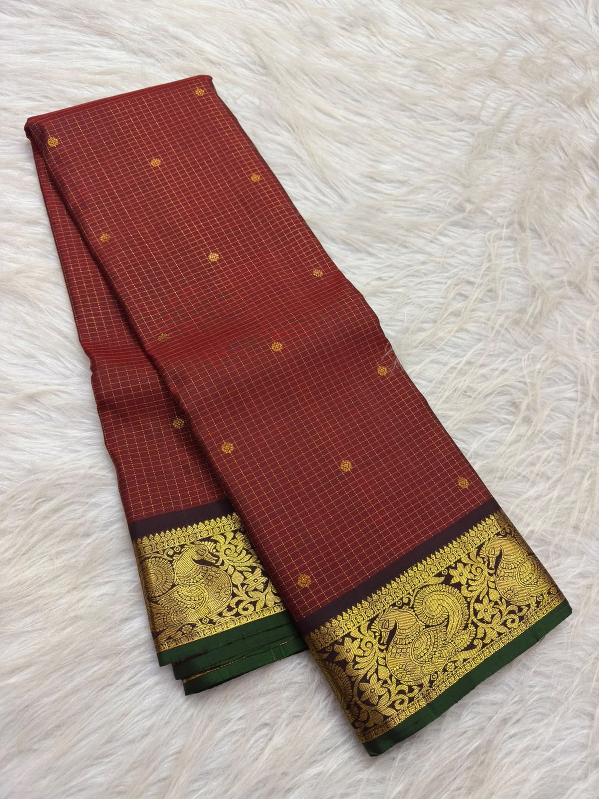 Dark plum-toned border with gold peacock and malar kodi floral vine zari and deep-green selvedge on vermilion red Kanchipuram silk saree