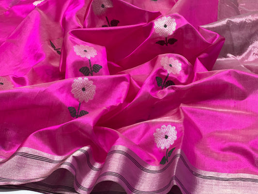 Close-up of a pale flower with dark centre and green leaves on fuchsia Chanderi.