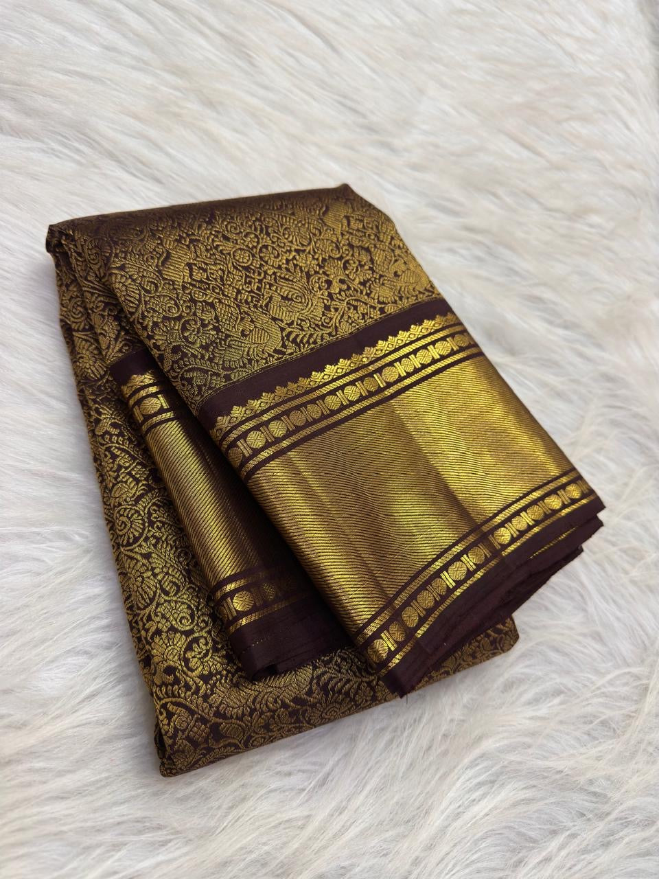 Close-up of the gold zari floral jaal on the deep cinnamon brown Kanchipuram saree, showing vines, blossoms, and peacock motifs