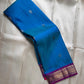 Draped teal blue Pure Kanchipuram silk saree showing scattered zari buttas and a purple border with zari woven pattern work.