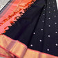 Folded pure Kanchipuram silk saree in purple black tones showing silk texture and shimmering zari border detail.
