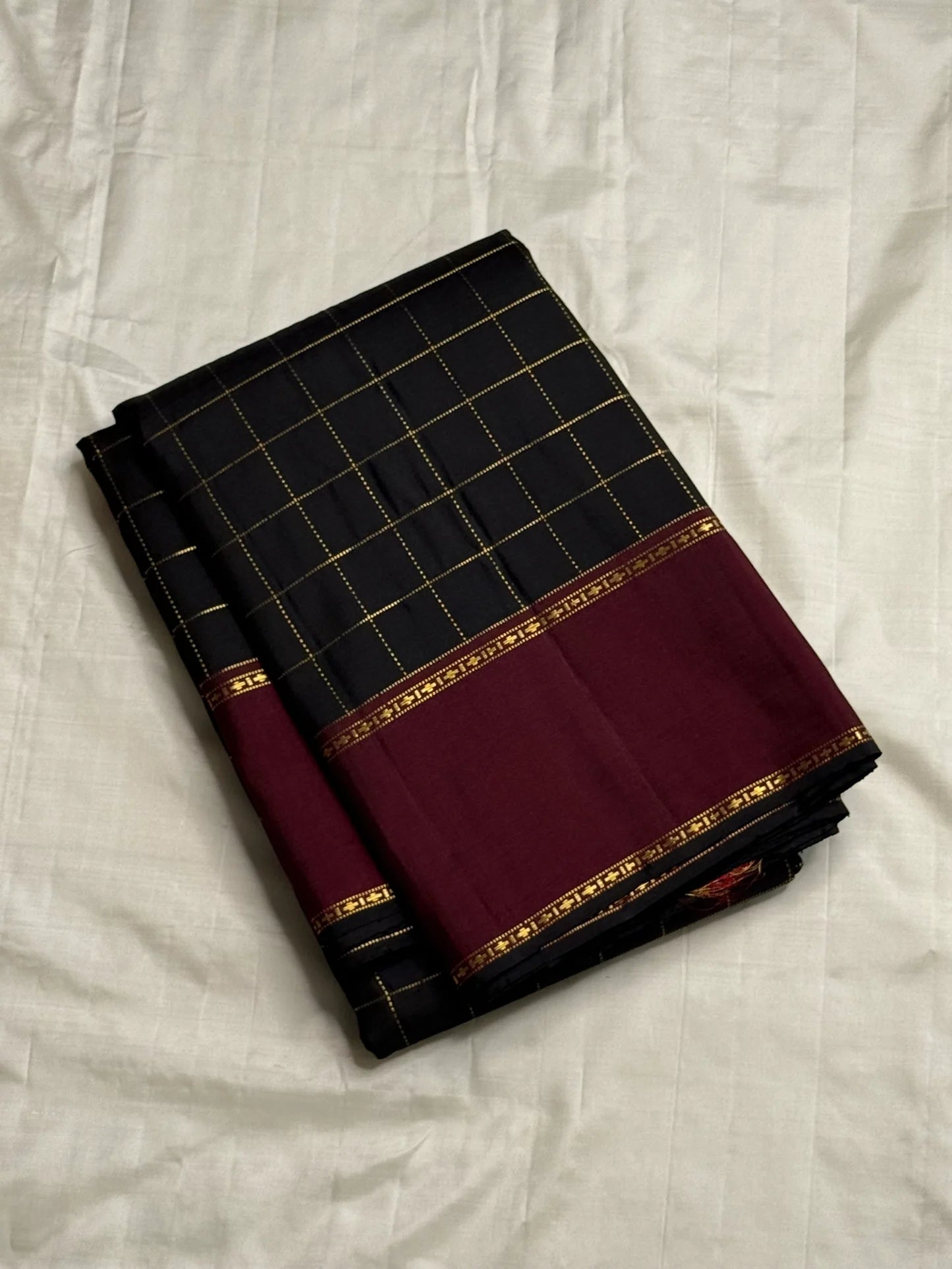 Folded Pure Kanchipuram Silk Saree in black checked weave with wide maroon zari border on ivory backdrop