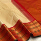 Close-up of red zari woven border with green edging on an ivory pure Kanchipuram silk saree, with tassels visible.