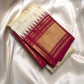 Folded ivory Pure Kanchipuram silk saree with kattam checks, zari buttas, and a tomato red zari woven border.
