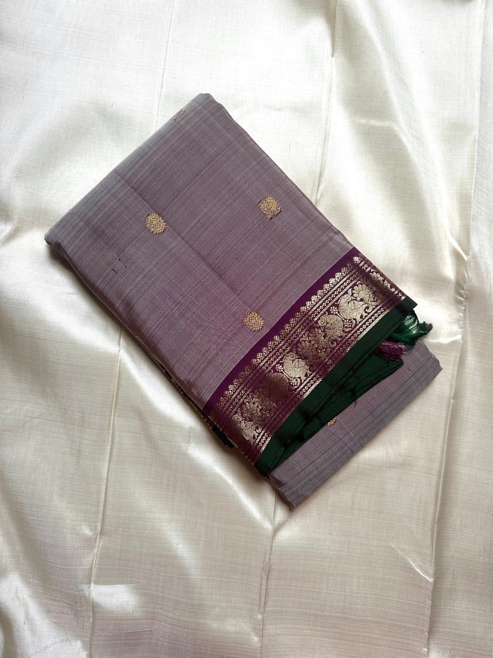 Folded grey pure Kanchipuram silk saree with gold butti and purple zari woven border, shipped from New Jersey USA.