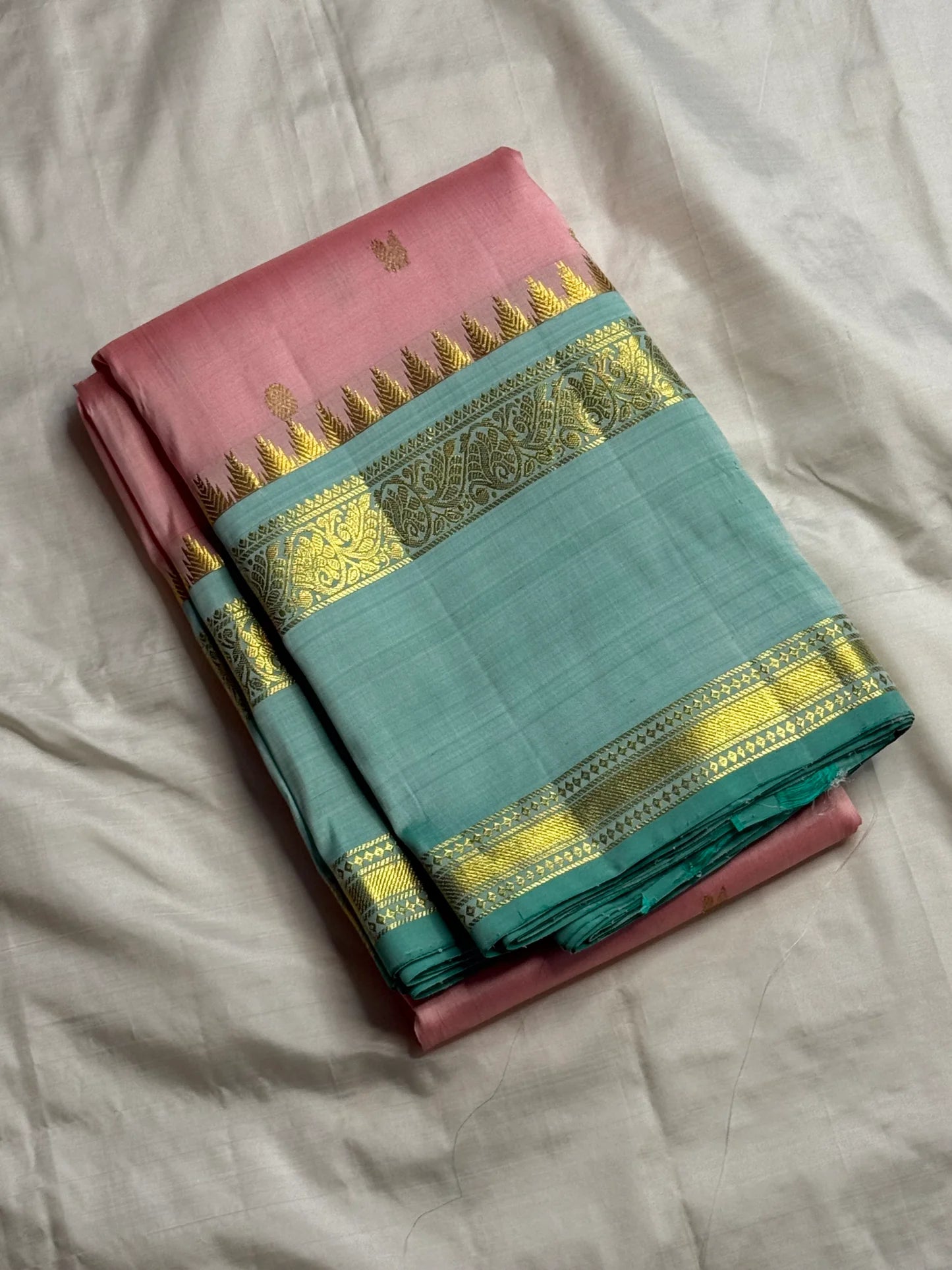 pink kanchipuram silk saree folded with sea green zari woven border