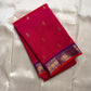 Pure Kanchipuram silk saree folded in rani pink with small gold zari buttas and a blue zari woven border.