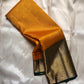 Mustard yellow Pure Kanchipuram silk saree draped to show dark green edge and wide zari woven gold border.